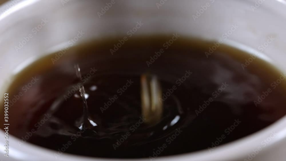 Drop of freshly brewed tea falling into the cup. Slow motion video. Drop of freshly brewed tea falling into the cup. Slow motion video.