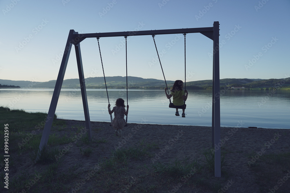 children on a swing by the lake in evening