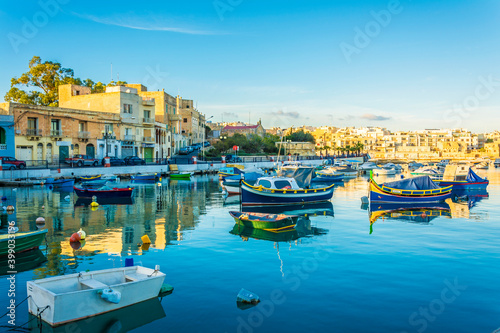 Colorful painted wood boats with the typical protective eyes on a sunny day in Marsaxlokk, Malta. © nejdetduzen