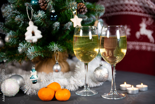 new year's still life, 2 glasses of champagne tangerines on the table on the background of the Christmas tree