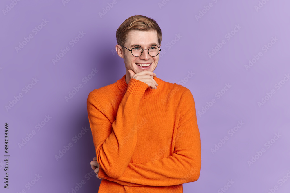 Φωτογραφία Studio shot of handsome cheerful guy holds chin recalls something funny happened
