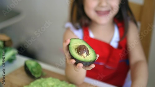 Little girl at a table happily showing an avocado
