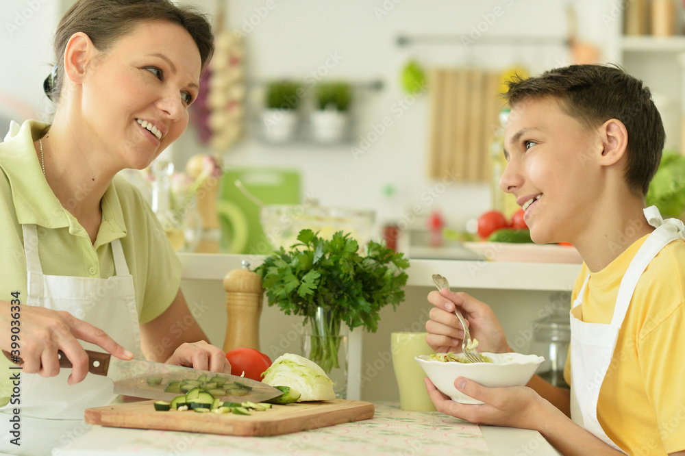 Mother and son eating fresh salad at kitchen Mother and son eating fresh salad at kitchen