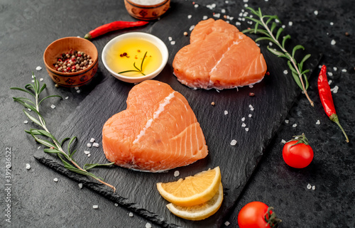 Two raw salmon fillets with heart shaped spices on a stone background