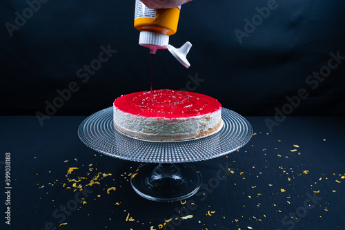 Cheesecake with berries on black background. Pouring sauce on chessecake photo