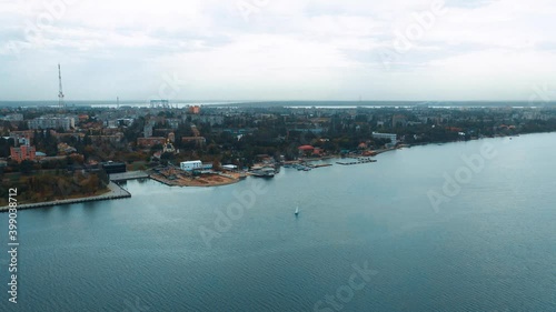 Top view on the sailing yacht in the river near the beautiful city. View from above on the boat in the water. Outdoor leisure. photo