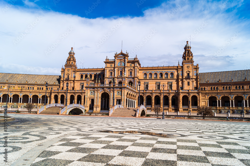 Front view of the main building in the Plaza de España in Seville (Andalusia, Spain). Emblematic place of the city next to the María Luisa Park on a day with clouds and puddles of water on the ground.
