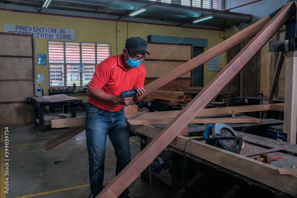 The carpenter using cordless drill for installing roof rafters on a new gazebo construction project The carpenter using cordless drill for installing roof rafters on a new gazebo construction project
