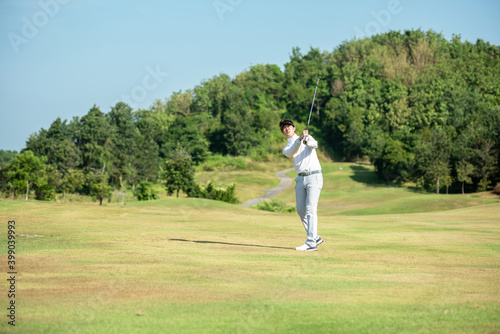 Golfer asian man use iron swing and hitting golf ball practice at golf driving range and fairway in sunny morning day on club golf. 