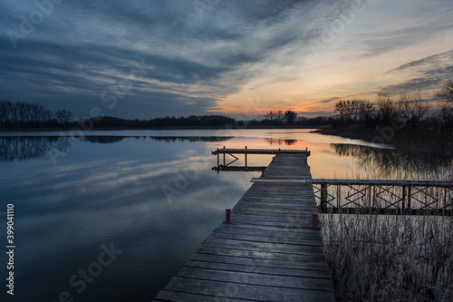 Long wooden bridge on the lake and sunset clouds © darekb22