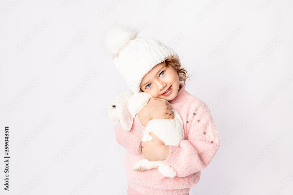 a little girl in winter clothes holds a rabbit on a white background. New year's concept, space for text a little girl in winter clothes holds a rabbit on a white background. New year's concept, space for text