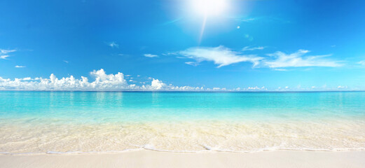 Beautiful sandy beach with white sand and rolling calm wave of turquoise ocean on Sunny day on background white clouds in blue sky. Island in Maldives, colorful perfect panoramic natural landscape.