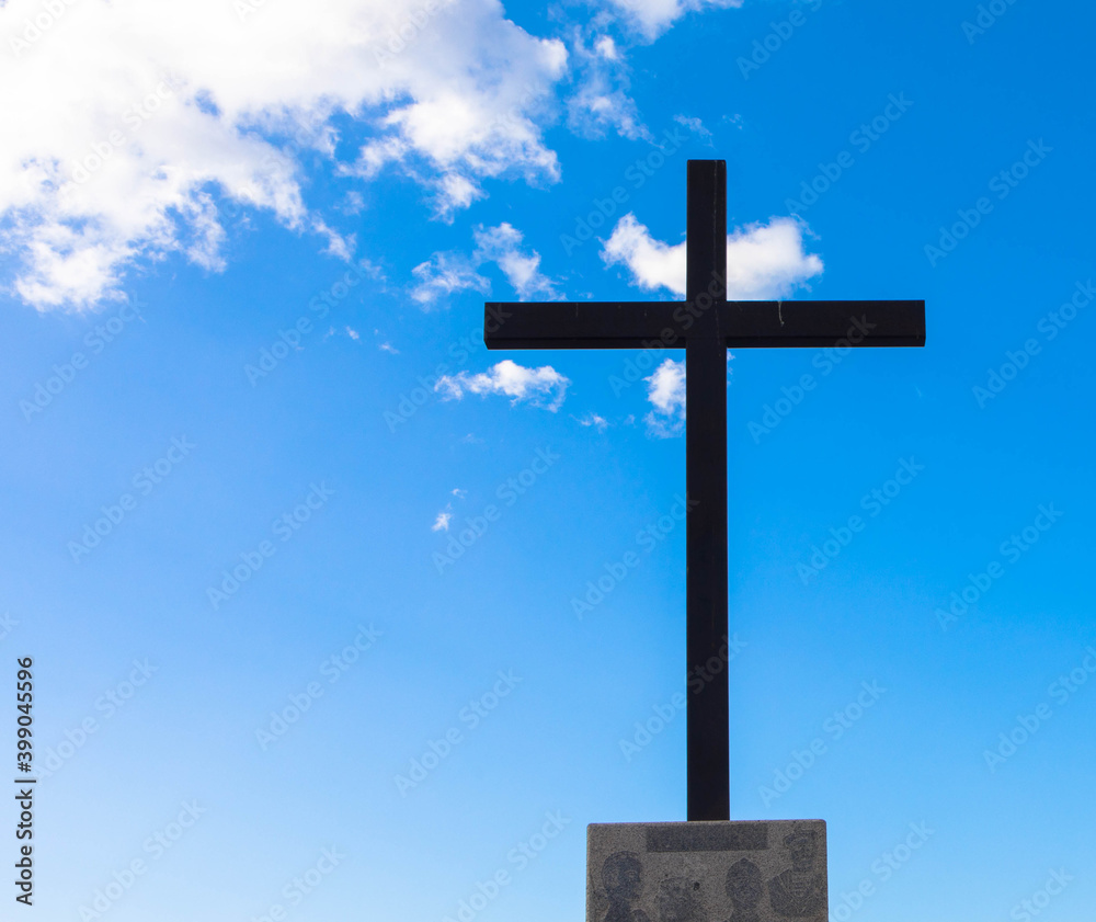 Religious cross on a beautiful partly cloudy blue sky, copy space