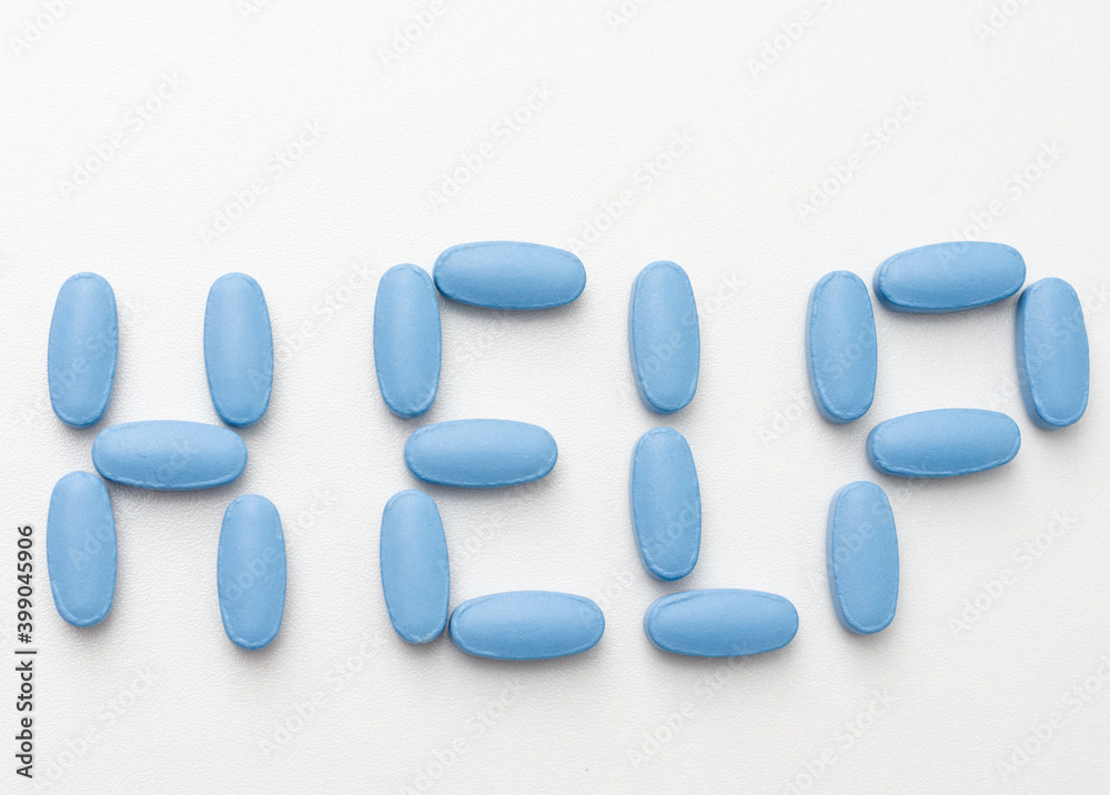Close- up of HELP  word written  with  blue pills on white background .