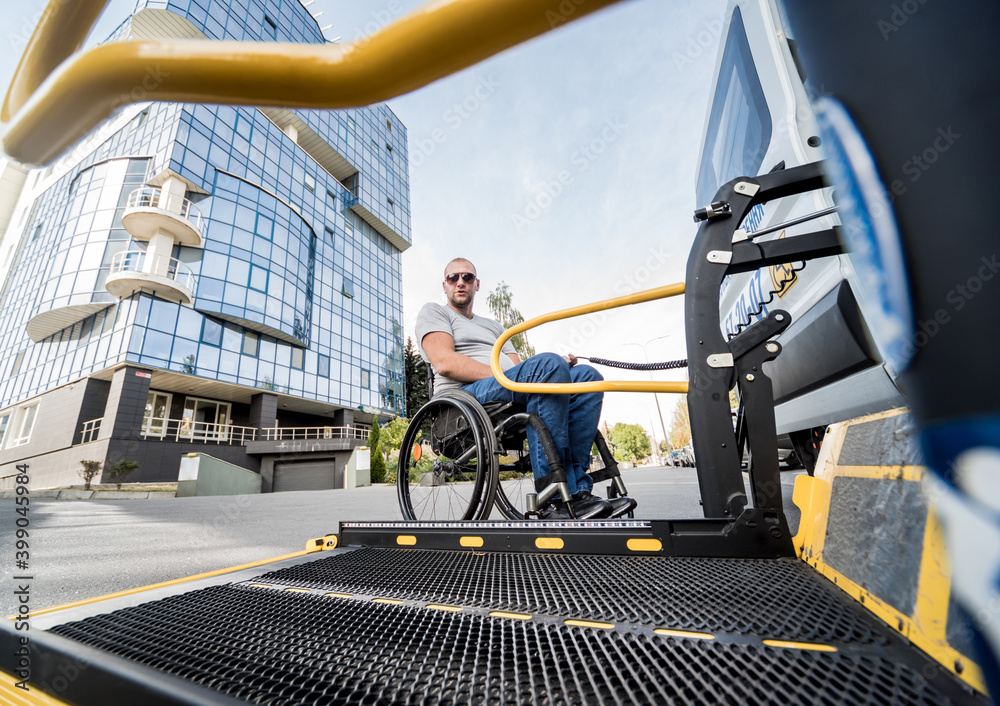 A man in a wheelchair moves to the lift of a specialized vehicle A man in a wheelchair moves to the lift of a specialized vehicle