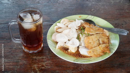 Kupat Tahu, a traditional Javanese Indonesian food containing kupat, fried tofu, cabbage, bean sprouts, and peanut sauce. There is a glass of iced tea
