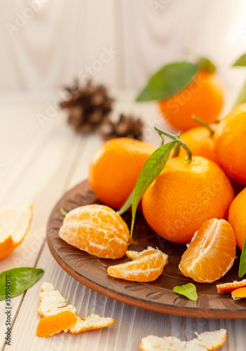 slices of tangerine in a rustic plate on white wooden background, still life of bright mandarins, seasonal fruits, christmas eve