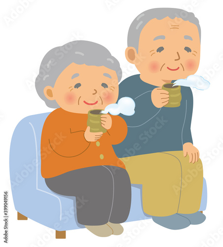ソファに座って日本茶を飲む高齢者。おじいさんとおばあさん。