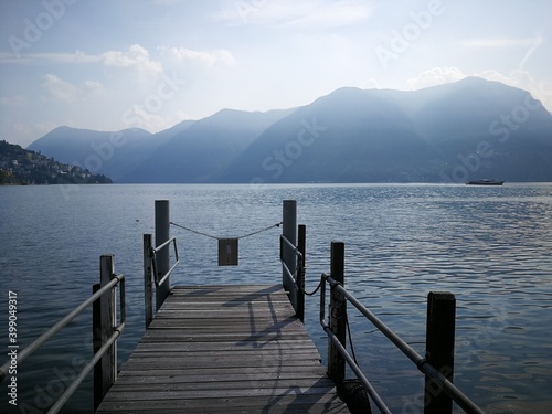 Wooden pier in the Lugano lake, Sitzerland with mountains in the background © ivva100