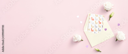 Happy Valentines Day banner template. Flat lay paper envelope, greeting card and rose flowers on pink background. Top view with copy space.