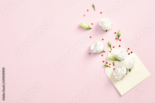 Flowers in envelope and red confetti on pink background. Flat lay, top view, copy space. Love letter, romantic concept. Happy Valentines day greeting card design. © photoguns