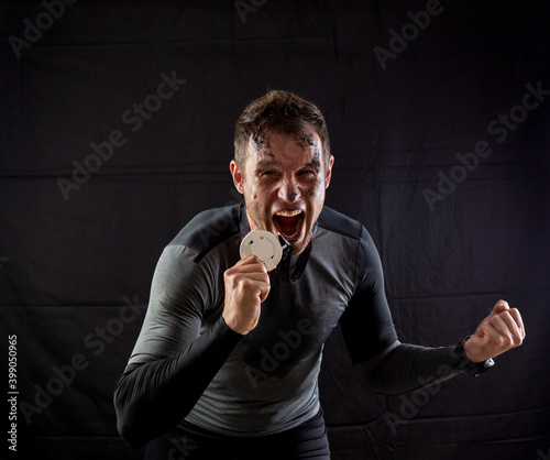Handsome man in sportswear is insanely rejoicing at the received silver medal in the studio on a black background