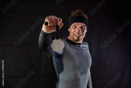 Handsome man in sportswear is insanely rejoicing at the received silver medal in the studio on a black background