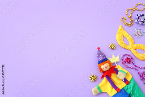 carnival party celebration concept with mask and colorful party accessories over purple wooden background. Top view