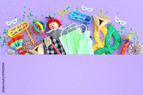 Purim celebration concept (jewish carnival holiday) over purple background. Top view, Flat lay. Coronavirus prevention concept, medical mask and sanitizer gel