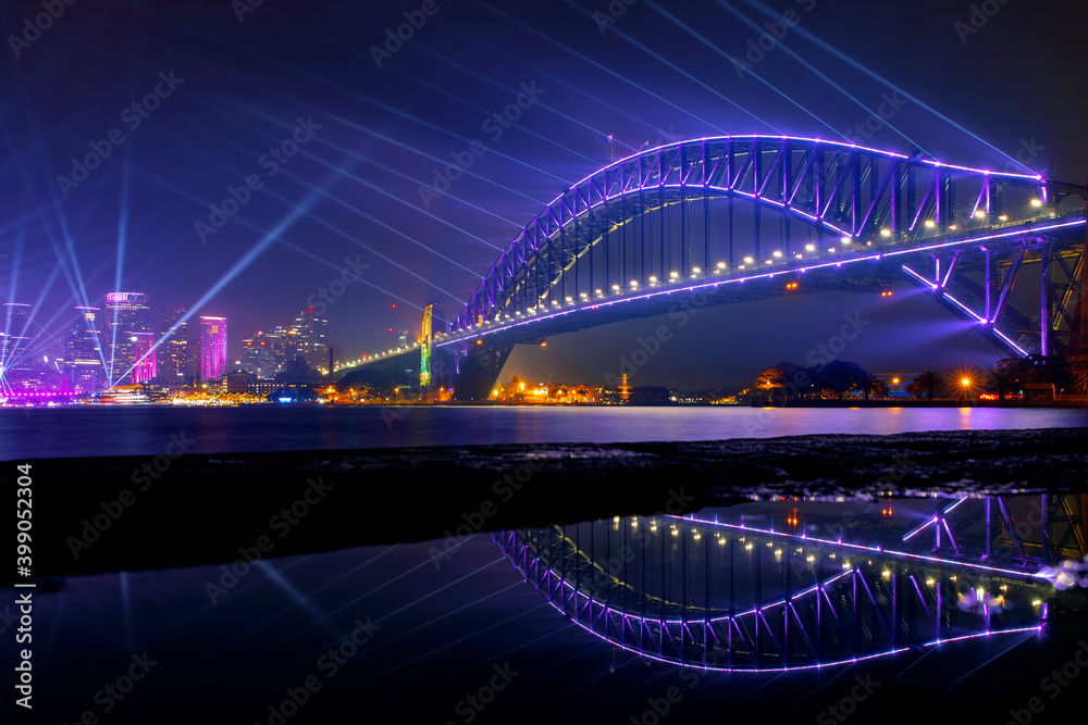 Sydney Harbour Bridge at night with beaming lights for Vivid Festival. View from Kirribilli puddle