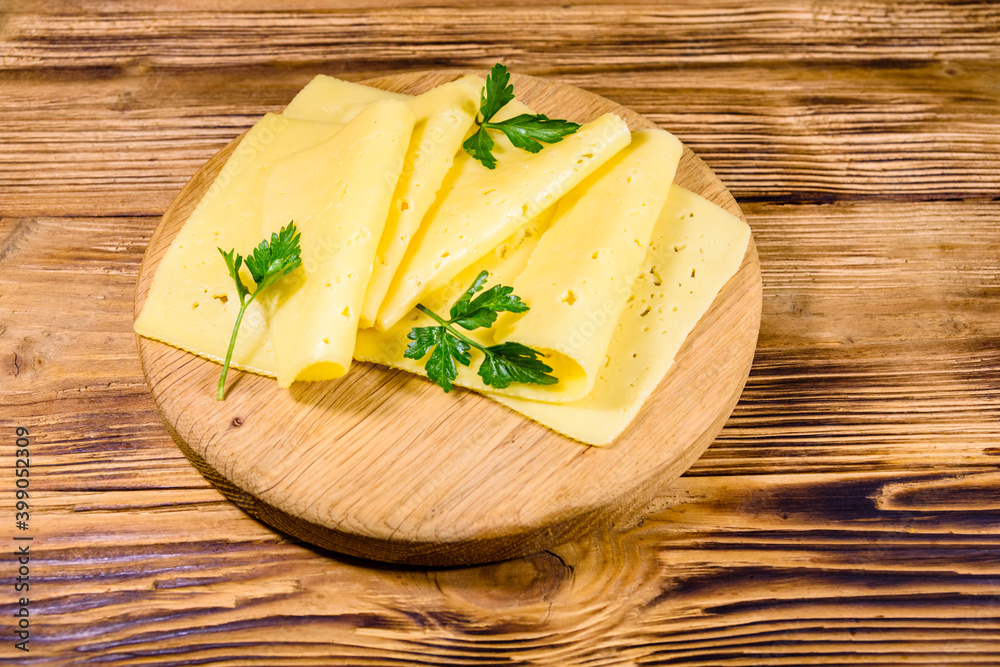 Sliced cheese and parsley on a wooden cutting board