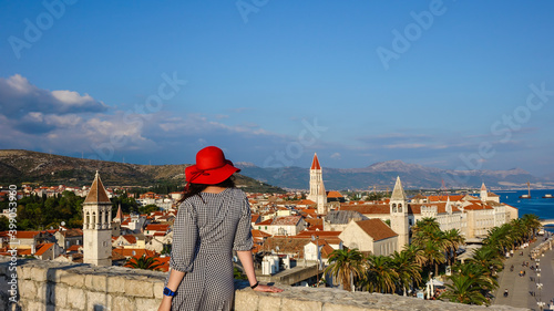 Girl with red hat standing at Tower Kamerlengo overlooking the Trogir Old Town photo