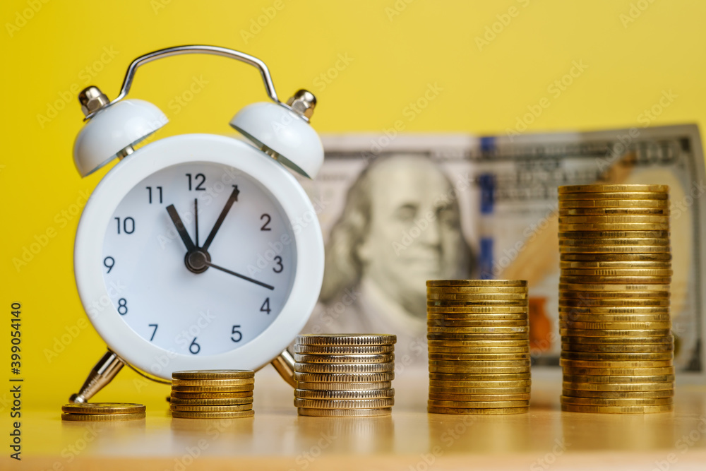 Stacks of coins in row ascending and alarm clock with 100 dollars banknote on background. Time is money, efficient business, great income in short time concepts. Stacks of coins in row ascending and alarm clock with 100 dollars banknote on background. Time is money, efficient business, great income in short time concepts.