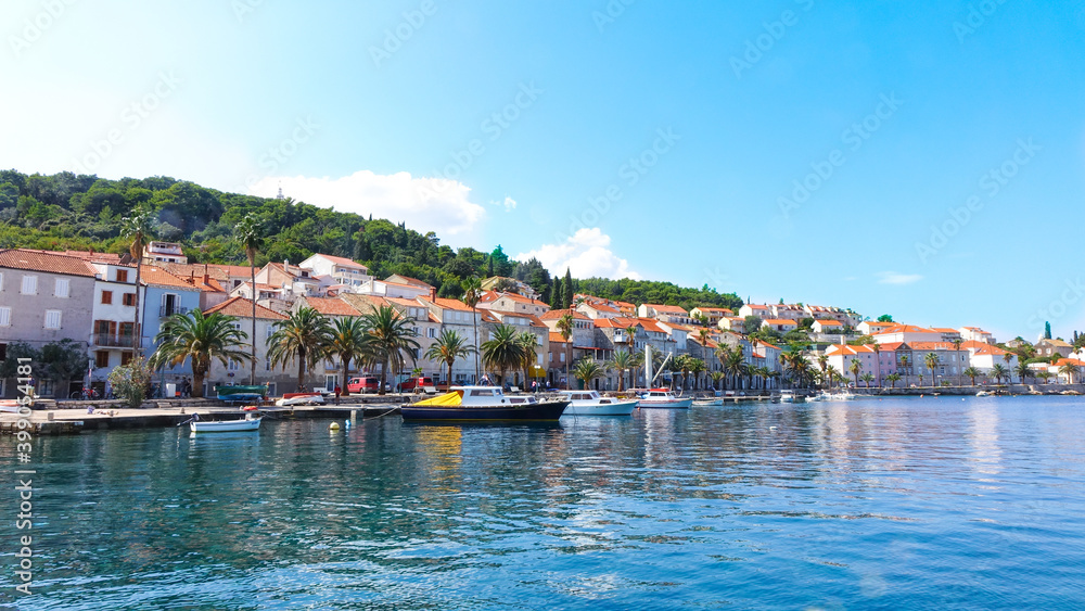 Panoramic view of Korcula coast with mountains, houses and boats on the harbor