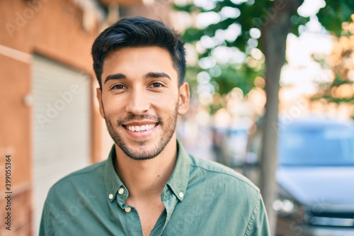 Young latin man smiling happy walking at the city. photo