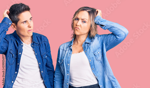 Couple of women wearing casual clothes confuse and wondering about question. uncertain with doubt  thinking with hand on head. pensive concept.