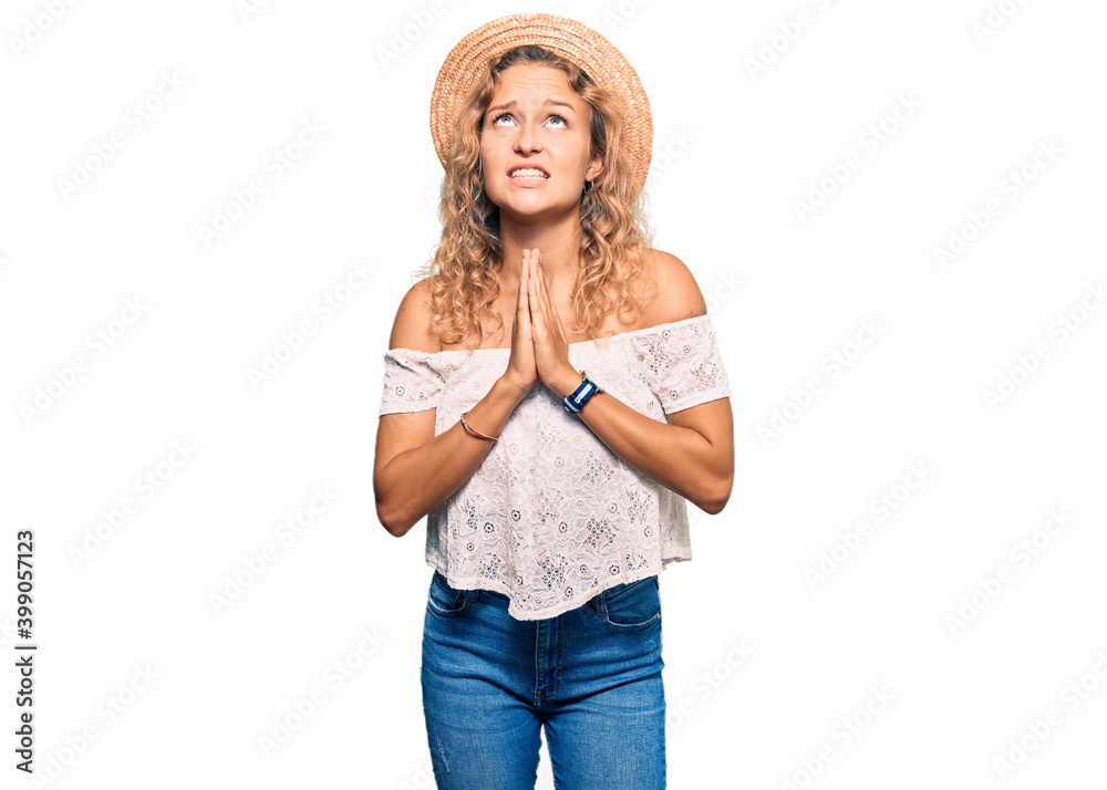 Beautiful caucasian woman wearing summer hat begging and praying with hands together with hope expression on face very emotional and worried. begging. Beautiful caucasian woman wearing summer hat begging and praying with hands together with hope expression on face very emotional and worried. begging.
