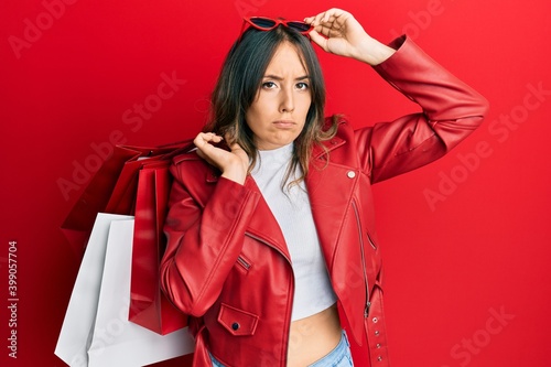 Young brunette woman holding shopping bags skeptic and nervous, frowning upset because of problem. negative person.