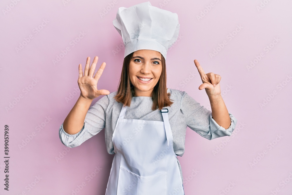 Young beautiful woman wearing professional cook uniform and hat showing and pointing up with fingers number seven while smiling confident and happy. Young beautiful woman wearing professional cook uniform and hat showing and pointing up with fingers number seven while smiling confident and happy.