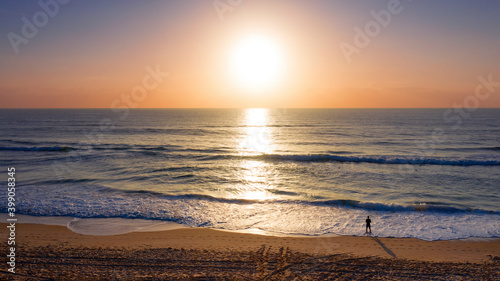Person standing on beach at sunrise 