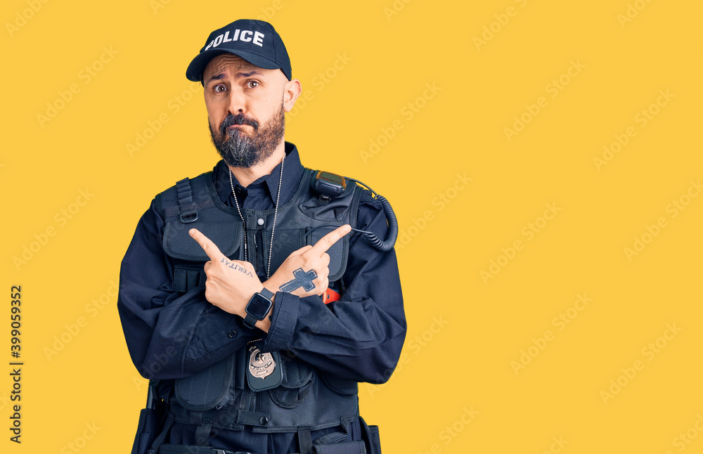 Young handsome man wearing police uniform pointing to both sides with fingers, different direction disagree Young handsome man wearing police uniform pointing to both sides with fingers, different direction disagree