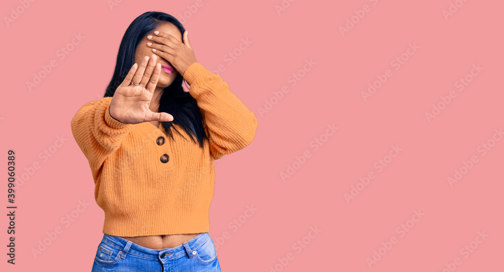 Hispanic woman with long hair wearing casual winter sweater covering eyes with hands and doing stop gesture with sad and fear expression. embarrassed and negative concept.