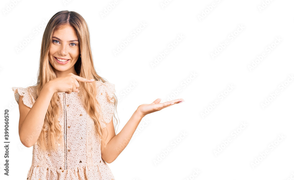Beautiful caucasian woman with blonde hair wearing elegant summer clothes amazed and smiling to the camera while presenting with hand and pointing with finger. Beautiful caucasian woman with blonde hair wearing elegant summer clothes amazed and smiling to the camera while presenting with hand and pointing with finger.