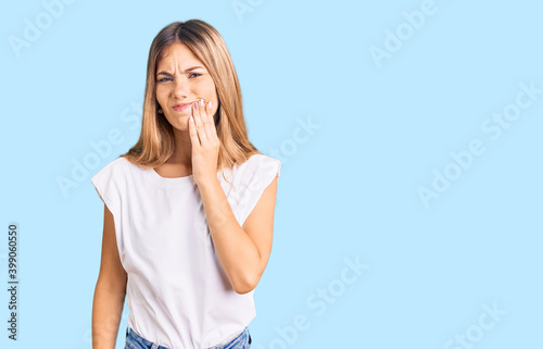 Beautiful caucasian woman with blonde hair wearing casual white tshirt touching mouth with hand with painful expression because of toothache or dental illness on teeth. dentist