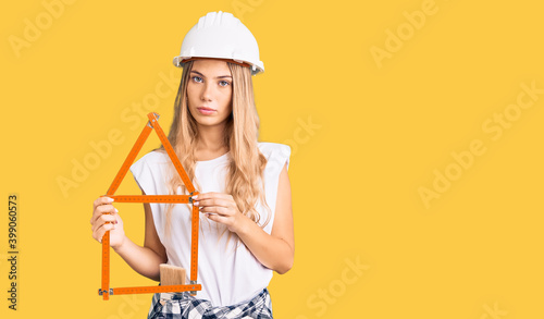 Beautiful caucasian woman with blonde hair wearing architect hardhat and holding tools thinking attitude and sober expression looking self confident © Krakenimages.com