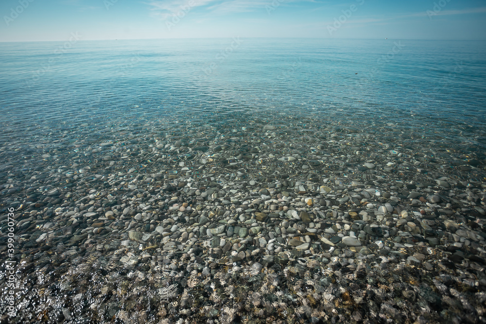 Transparent water on the seashore through which the shiny sea stones are visible