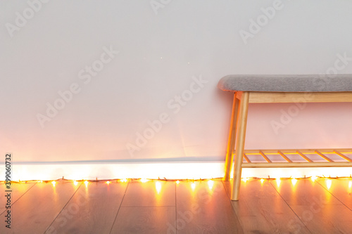 a bench near a gray wall and a garland with lights photo