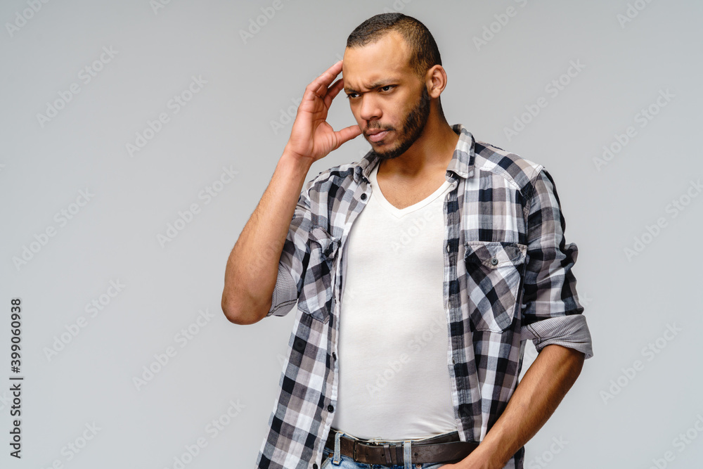 Studio shot of a serious african-american manwearin casual wear with headache Studio shot of a serious african-american manwearin casual wear with headache