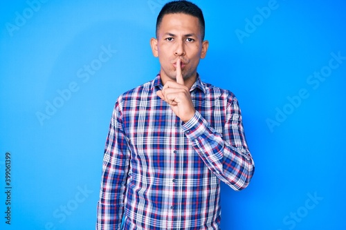 Young handsome latin man wearing casual clothes asking to be quiet with finger on lips. silence and secret concept.
