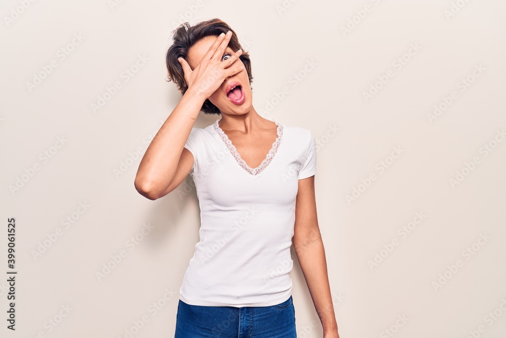 Young beautiful woman wearing casual clothes peeking in shock covering face and eyes with hand, looking through fingers with embarrassed expression. Young beautiful woman wearing casual clothes peeking in shock covering face and eyes with hand, looking through fingers with embarrassed expression.